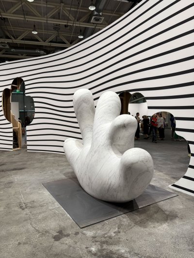 A curved black-and-white, striped wall with a cutout before which stands a marble cactus.