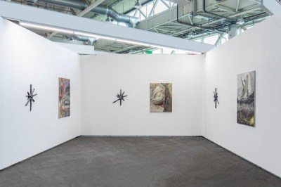 A white-walled booth with paintings on the wall.