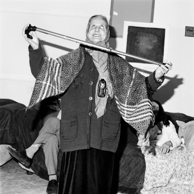 A woman in a headscarf balancing a cane between her two hands.