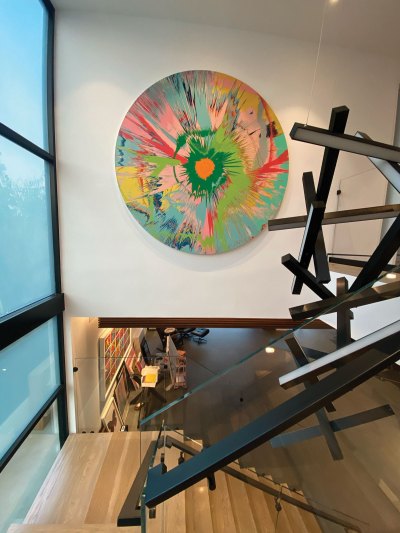 A stairwell with a circular abstract painting hanging on a wall. 