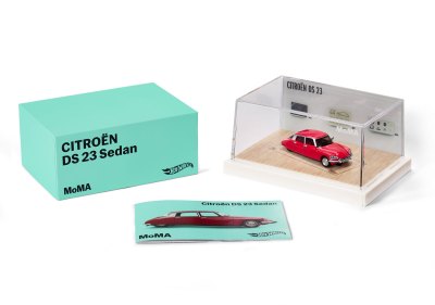 A Red Hot Wheel in its box next to the box cover and a brochure. 