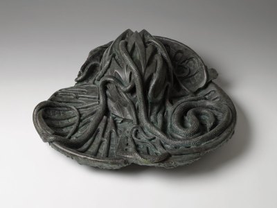 A bronze sculpture of a vine-like, snake-like tendrils coming out of an egg.