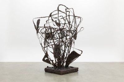 An abstract sculpture in bronze that looks like a various spindles orbiting around an axis.