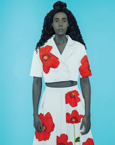 A portrait of a Black woman in a white and red floral jacket and skirt against a sky blue background.