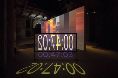 A multimedia video installation showing the number 00:47:02 on one screen.