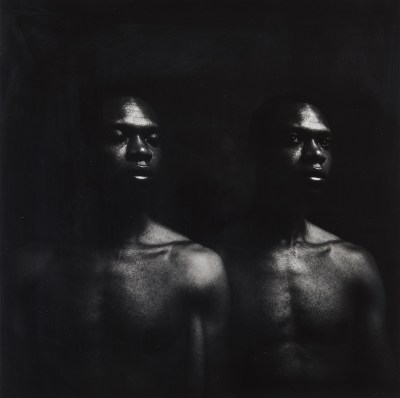 A photograph of two Black men in moody, dark lighting.