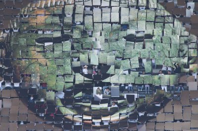 People hold up posters to make a composite image of a pre-Columbian artifact in a football/soccer stadium. 