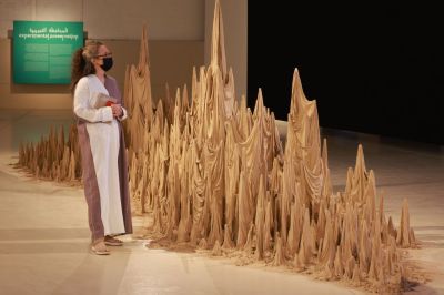 A woman starting at a sculpture resembling a cloth draped over pointed forms.