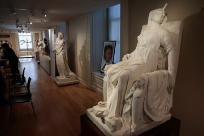 A sculpture of a woman in a chair with her head turned upward.