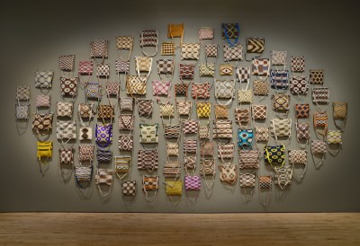 A group of 100 bags hung to a wall.