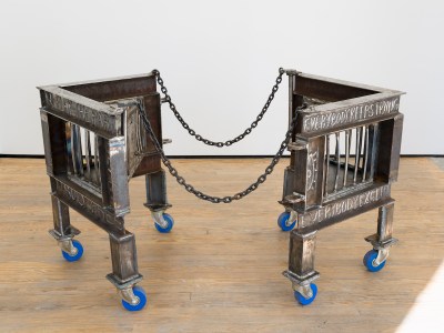 A cage-like structure on wheels in two halves, with chains linking its parts.