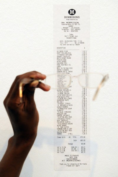 A person holding a pair of glasses over a receipt.