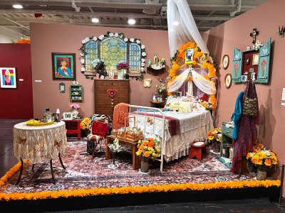 View of an installation re-creating a maximilist bedroom with a home altar. 