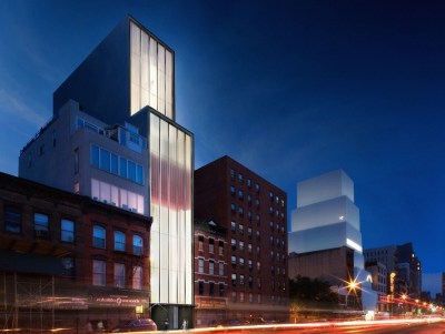 A towering gallery building abutting a street where out-of-focus cars zoom by.