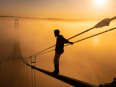 A photo of a man scaling a bridge at sunset.