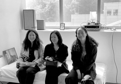 Portrait of Binna Choi, Goen Choi, and Hyeree Ro sitting on a bed.