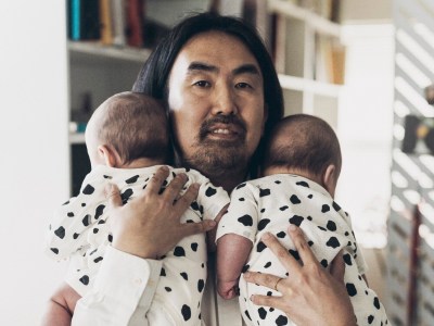 A Japanese man with long hair holds twin babies.