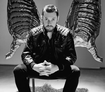 A man seated beneath two golden wings.