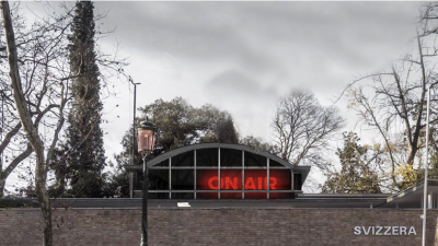 A building with a glowing 'ON AIR' symbol visible through its roof.