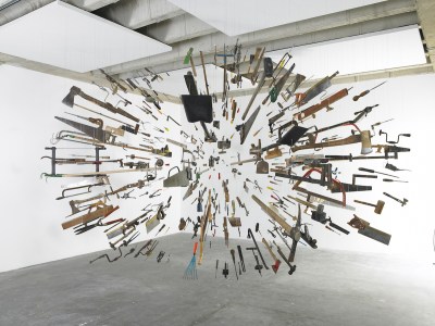 An installation composed of hanging saws and knives arranged so that they appear to be flying toward each other.