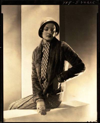 A woman in a dress and scarf seated on a balcony.