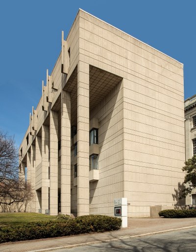 A photo shows the modernist List Art Center at Brown University in Rhode Island. It is clad in light-colored stone and has a modernist colonnade on the facade.