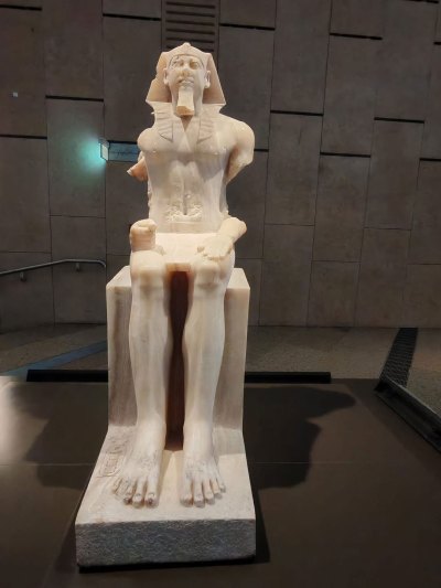 A statue of a seated Pharaoh that has its arms missing.