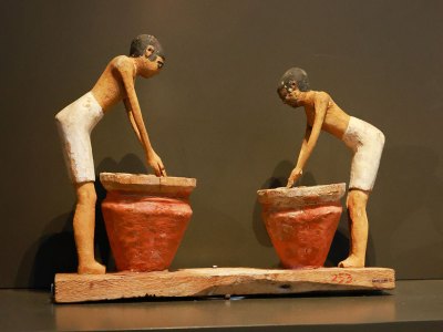 an ancient artifact of two figures making beer at two large jars.